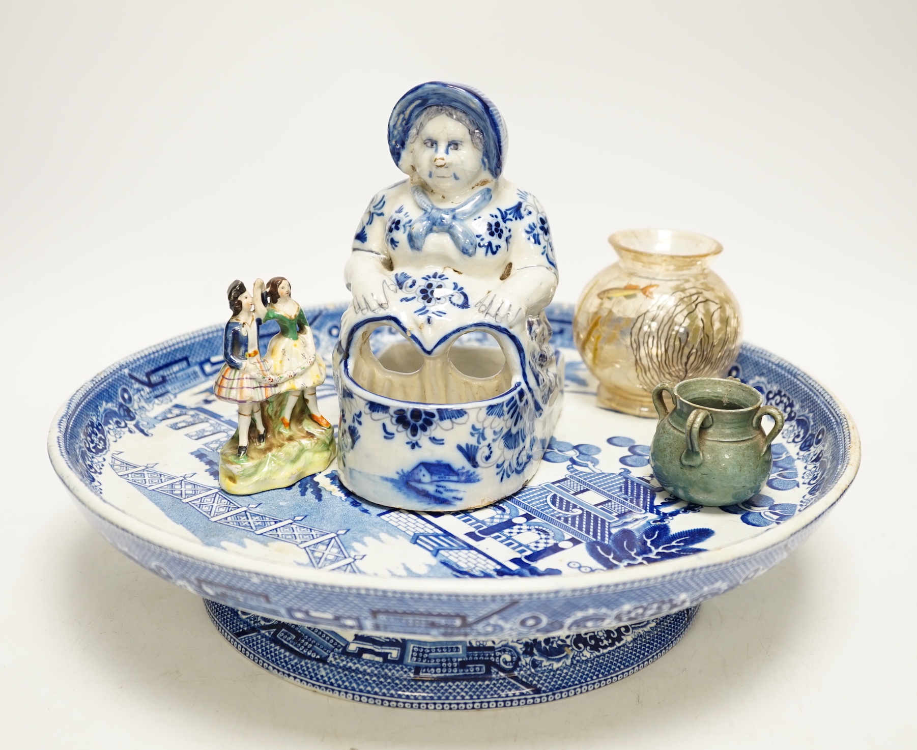 A group of mixed ceramics including a Moser crackle glass fish vase, Delft seated lady figurine, willow pattern comport, figural soap dish, maiolica match strike etc.